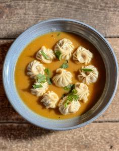 a bowl of dumpling soup on a wooden table at Xanadu Homes in Jomsom +13 photos