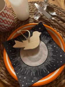 a table with a plate with a wooden bird on it at Maison d'hôtes des Mondfänger in Meisenthal