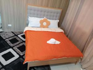 a bed with a orange blanket and a hat on it at matthew's cozzy staycation suit in Sampong