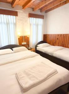 two beds in a room with wooden walls and windows at Xanadu Homes in Jomsom