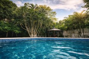 a swimming pool with a gazebo and trees at Quinta en Melgar piscina BBQ cerca a Piscilago in Melgar