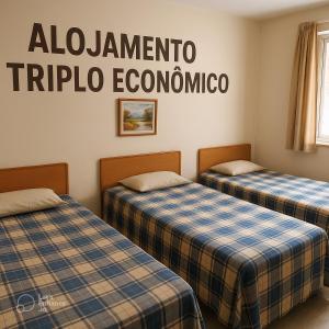 two beds in a room with a sign on the wall at Alojamento Pousada Economica Canoas in Canoas