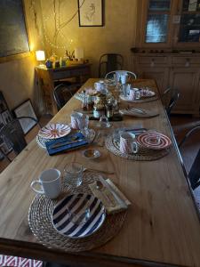 a wooden table with plates and cups on it at Maison d'hôtes des Mondfänger in Meisenthal