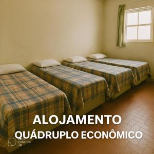 three beds in a room with a window at Alojamento Pousada Economica Canoas in Canoas