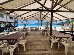 a patio with tables and chairs and the beach at Ohlala Guesthouse in Perhentian Islands