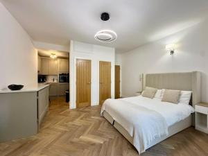 a bedroom with a white bed and a kitchen at West Cliff Studio - Private Garden mins from Beach in Bournemouth