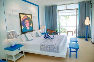 a bedroom with a white bed with a painting on the wall at Norea Sands in Bentota