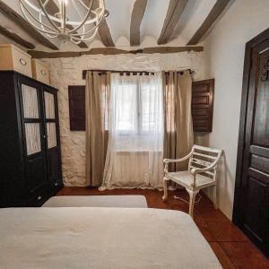 a bedroom with a bed and a chair and a window at Casa Rural Concejos in San Román de Cameros