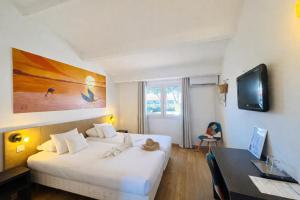 a hotel room with two beds and a desk and a table at Artemia Aigues-Mortes - Hôtel avec piscine - Bornes électriques - Parking privé - Local vélo-moto in Aigues-Mortes