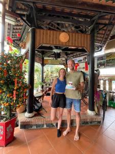 a man and a woman standing in front of a store at Terra Cotta Homestay in Hoi An