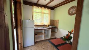 a kitchen with a white refrigerator and a sink at Vai Hea Lodge in Taputapuapea
