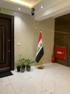a flag on a pole in a lobby with plants at Carmel Residence - كارمل ريزيدنس in Baghdād