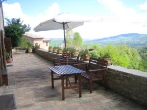 a table and chairs with an umbrella on a patio at Casa Vacanza La Valle in Urbino