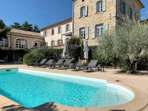 a swimming pool with chairs and a building at Château Meilhen in Les Mages