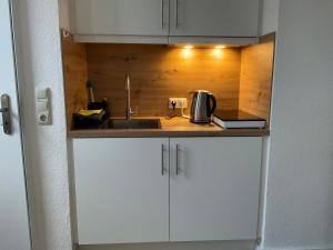 a kitchen with white cabinets and a sink at Ferienwohnung, Apartment Schwertherz in Wulfsen