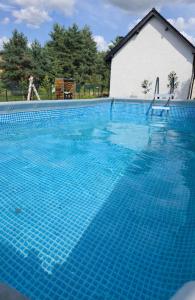 a swimming pool with two chairs in front of a house at W Olchach - lokal Klon in Wiktorowo