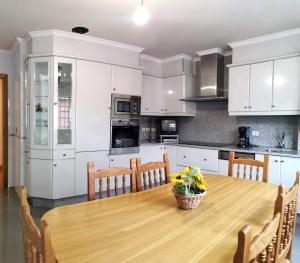 a kitchen with white cabinets and a wooden table at A DE NENO in Melide
