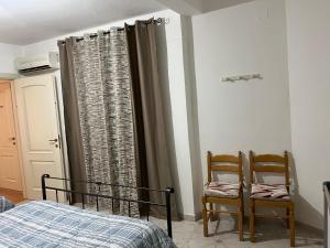 a bedroom with a bed and two chairs next to a window at Casa Petralia in Petralia Sottana