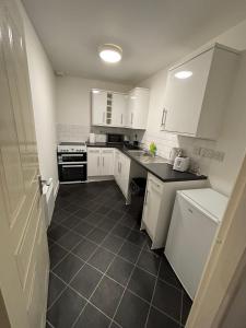 a kitchen with white cabinets and a black tile floor at Doncaster City Centre Immaculate 1 Bedroom flat in Doncaster +3 photos