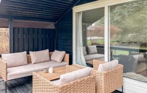 a screened in porch with wicker chairs and a table at 2 Bedroom Nice Home In Hundested in Hundested
