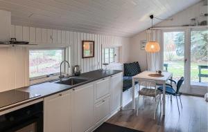 a kitchen with a sink and a table with chairs at 2 Bedroom Nice Home In Hundested in Hundested