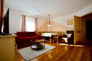 a living room with a red couch and a table at Almhaus Karantanien in Hochrindl
