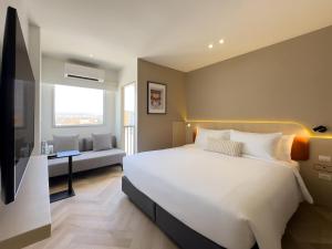 a bedroom with a large white bed and a couch at Fortune D Hotel Loei in Loei