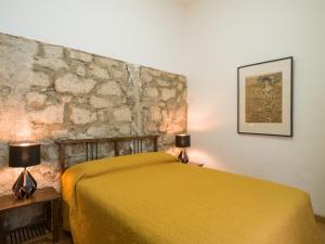 a bedroom with a yellow bed and a stone wall at Celia House in Las Palmas de Gran Canaria