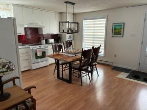 a kitchen and dining room with a table and chairs at Floral'Anse in LʼAnse-Saint-Jean