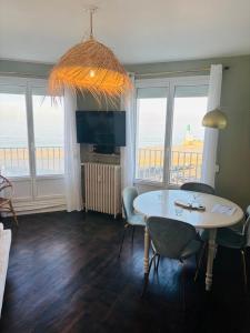 a living room with a table and chairs and a television at Le Gouvernail in Le Tréport
