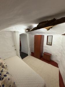 a small room with a bed and a small cabinet at Casa Cueva Conde in Guadix