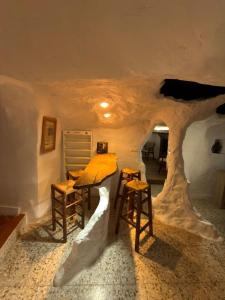 a table and two stools in a room with a tree on the ceiling at Casa Cueva Conde in Guadix