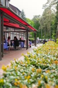 a patio with tables and chairs and people sitting at tables at Heidehotel Waldhütte in Telgte +10 photos