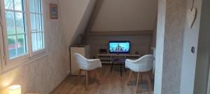 a living room with three white chairs and a television at L'HIBISCUS de l'Audière in Malaunay