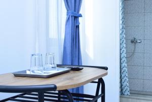 a wooden table with two glasses and a blue curtain at Hotel Road Rooms in Voluntari