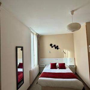 a bedroom with a bed with red pillows and a mirror at Le Saint Christophe in Cosne-Cours-sur-Loire +7 photos