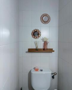 a white tiled bathroom with a toilet and a mirror at Alojamiento rural El Membrillo in Almodóvar del Río +4 photos