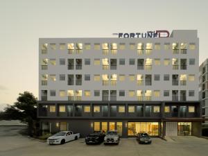 a tall building with cars parked in a parking lot at Fortune D Hotel Maesot in Mae Sot