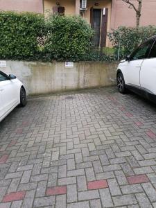 two white cars parked next to a wall at Casa Marta - tra vigne e motori in Castelvetro di Modena