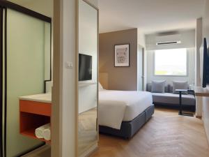 a hotel room with a bed and a mirror at Fortune D Hotel Maesot in Mae Sot
