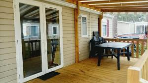 a screened in porch with a table on a deck at Sous les Pins dans camping 4 étoiles MH familial 322 6 à 8 couchages 2 salles de bain 2 WC in Saint-Julien-en-Born