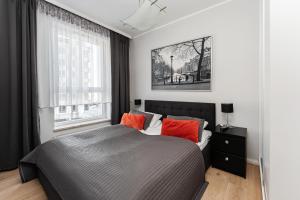 a bedroom with a bed with orange pillows and a window at Golden Apartments in Gdańsk