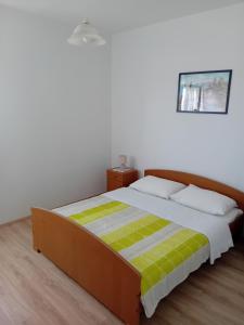 a bedroom with a bed with a green and yellow blanket at Dume in Povljana