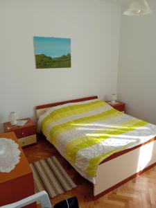 a bedroom with a bed with a green and white comforter at Dume in Povljana +4 photos