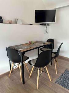 a dining room table with chairs and a television on a wall at Vörösdió apartment house in Szilvásvárad