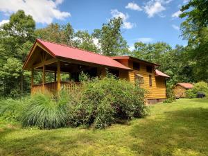 a wooden cabin with a red roof in a yard at Bison Farm - Cabin "Vieja" in Culpeper