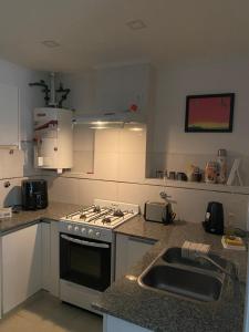 a kitchen with a sink and a stove top oven at Namante in Balcarce +12 photos