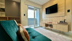 a living room with a green couch and a television at Studio Red 10 - Sorocaba in Sorocaba