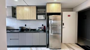 a stainless steel refrigerator in a kitchen with white cabinets at Studio Red 10 - Sorocaba in Sorocaba