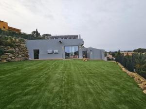 a dog laying on a lawn in front of a house at Casa Lou, architect villa with heated pool at Begur, 470m2 in Begur